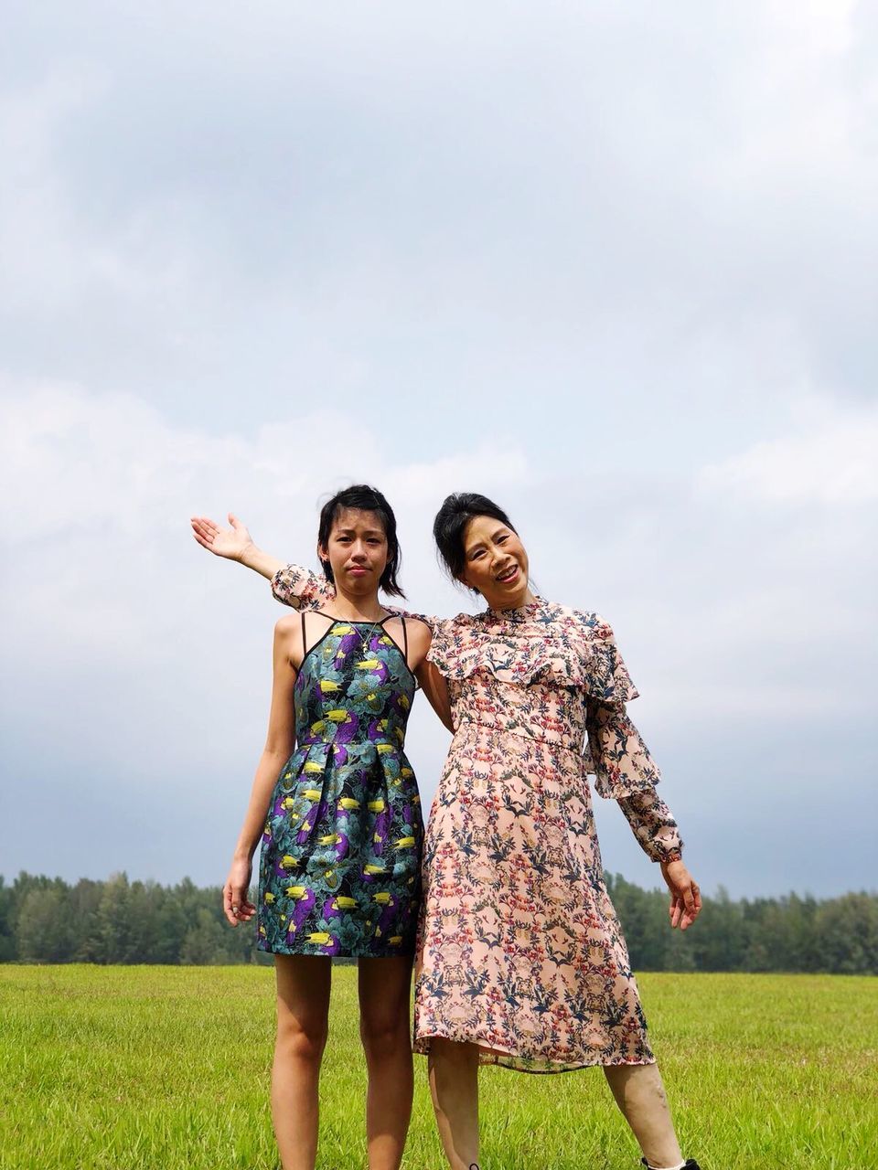 sky, real people, field, two people, grass, cloud - sky, casual clothing, leisure activity, three quarter length, outdoors, day, nature, lifestyles, togetherness, standing, landscape, smiling, happiness, beauty in nature, young women, scenics, tree, young adult, growth, friendship