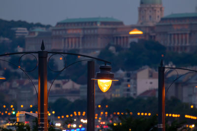 Illuminated street light in city at dusk