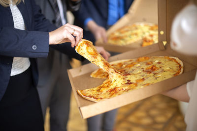Woman hand holding slice pizza from the box. selective focus