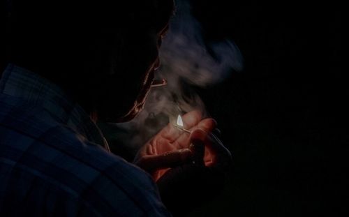 Man smoking cigarette against black background