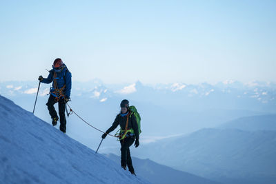 Two female mountaineers hike up a glacier on mt. baker, wa.