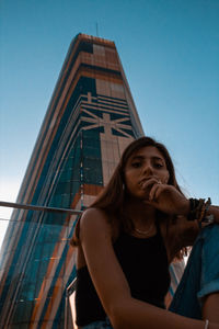 Low angle portrait of young woman against sky