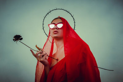 Low angle view of woman standing by red flower