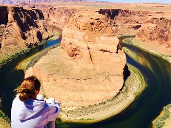 Rear view of woman sitting by horseshoe bend