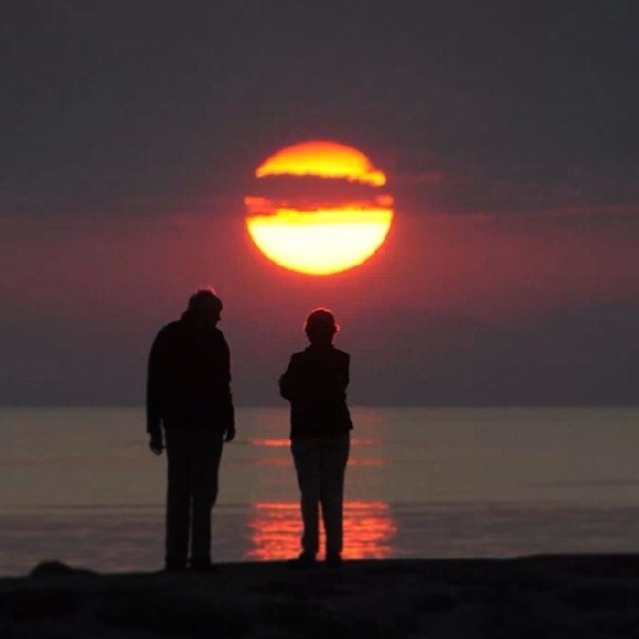 sunset, orange color, sea, silhouette, standing, water, lifestyles, beach, men, sun, leisure activity, horizon over water, rear view, scenics, person, full length, shore