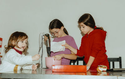 Three beautiful caucasian girls are baking cookies.