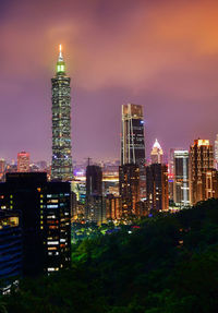 Illuminated buildings in city against sky at night