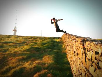 Full length of man jumping from stone wall