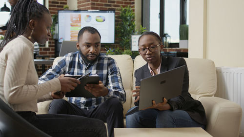 Friends using laptop while sitting at home