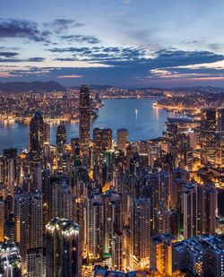 High angle view of illuminated city by sea against sky