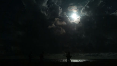 Silhouette people on beach against sky at night