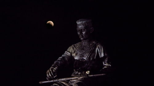 Statue against black background