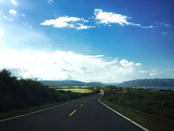 Scenic view of road by mountains against sky