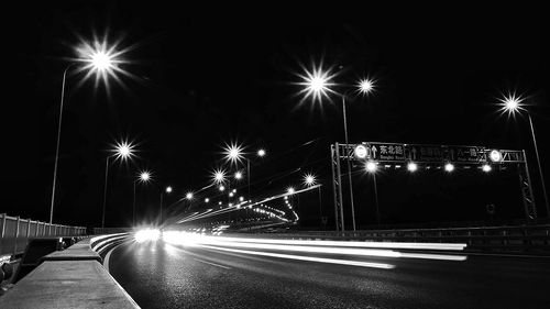 Light trails on road against sky at night
