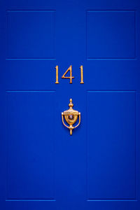 House number 141 on a blue wooden front door