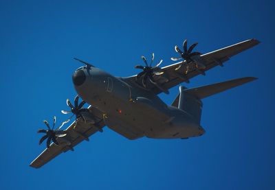 Low angle view of airplane against clear blue sky