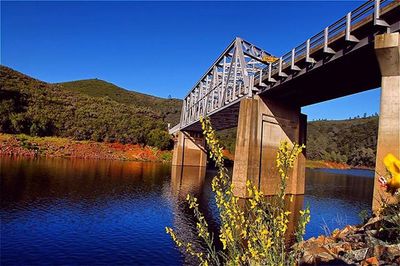 Bridge over river against clear blue sky