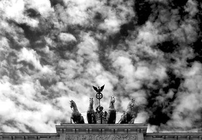 Low angle view of quadriga statue against cloudy sky