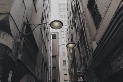Low angle view of illuminated street light against buildings