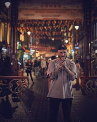 Portrait of man standing in city at night