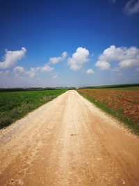 Road amidst field against sky