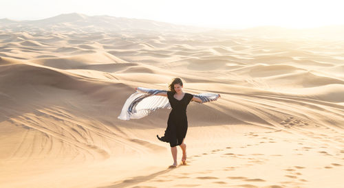 Full length of woman standing on sand dune in desert