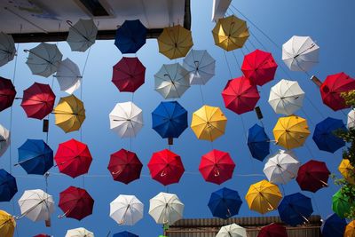Multi colored umbrellas hanging against sky