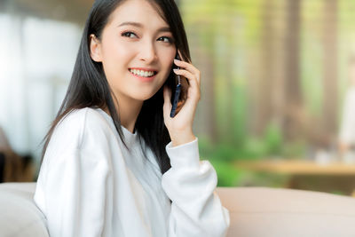 Portrait of smiling young woman using smart phone outdoors