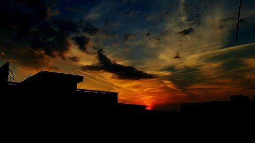Low angle view of silhouette buildings against dramatic sky