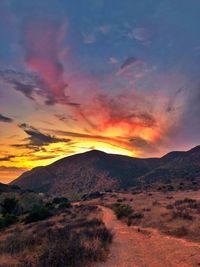 Scenic view of landscape against dramatic sky during sunset