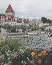 Scenic view of river by buildings against cloudy sky