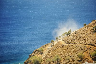 Scenic view of dirt road by calm sea