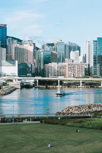 Buildings by river against sky in city