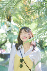 Portrait of young woman standing against trees