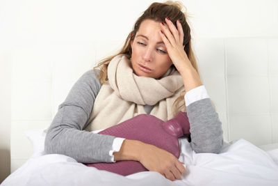 High angle view of ill woman lying on bed at home