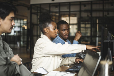 Businesswoman discussing with male colleague over computer at startup company