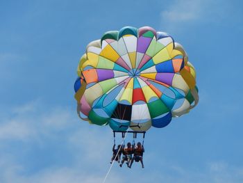 Low angle view of friends parasailing against sky