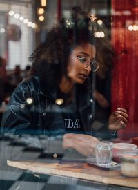 Young woman seen through window at cafe