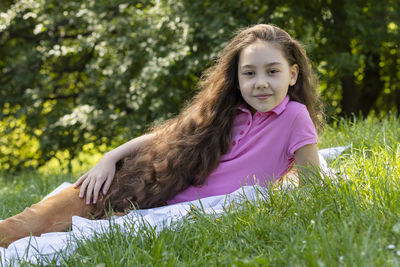 Little adorable girl with extra long hair lying on grass in meadow. caucasian asian brown haired