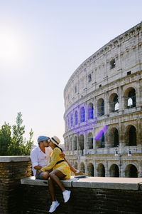 People sitting at historical building against sky