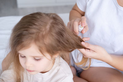 Mother tying daughter hair at home