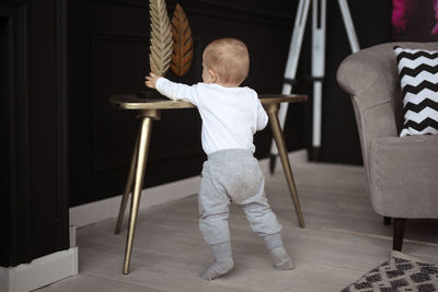 Baby 10 months in real interior, first steps. stretches to the statuette on the table.