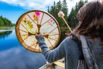 Reflection of woman holding umbrella on lake against sky