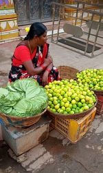 Woman sitting in leaves and fruits at market