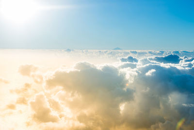 Airplane view of beautiful landscape with clouds, ocean with mountain peak and bright shining sun