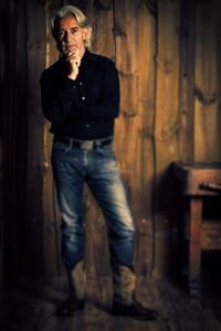 Full length portrait of young man standing against wall