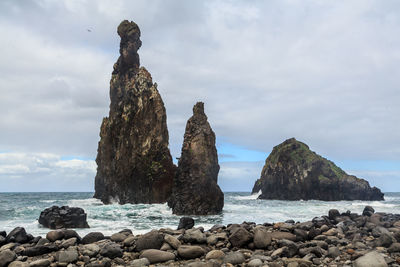 Rock formation on beach against sky