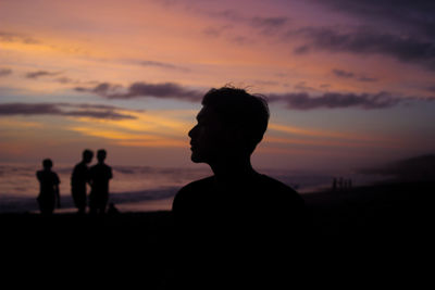 Silhouette people standing on land against sky during sunset