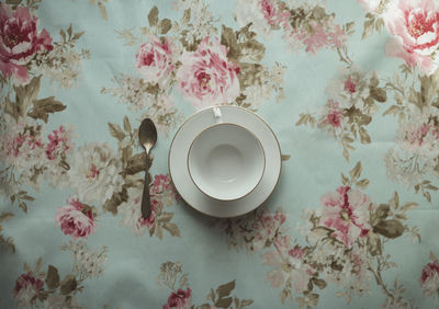 Cup of tea and spoon on a flowered background