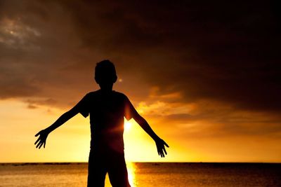 Silhouette of people on beach at sunset
